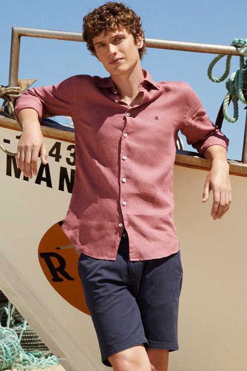 a man leaning against a boat in an Old Money casual aesthetic